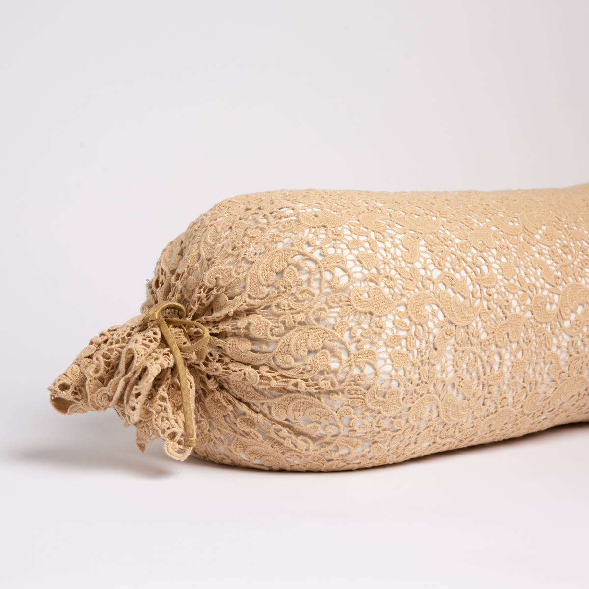 Honeycomb:  one end of a lace boslter cover on a winter white liner against a white background. 