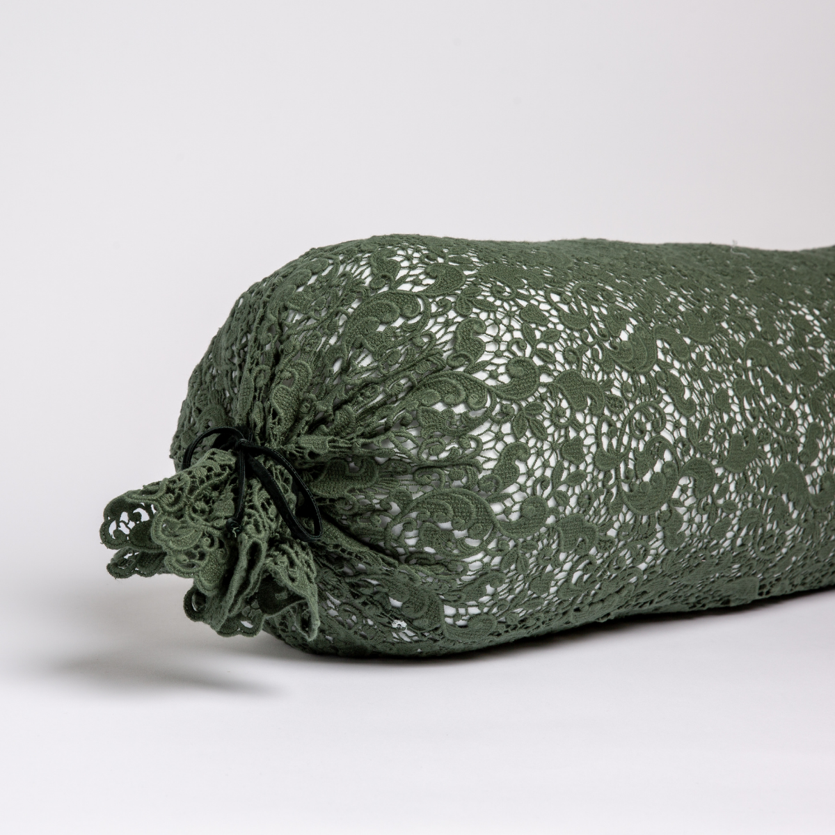 Juniper: one end of a lace boslter cover on a winter white liner against a white background. 