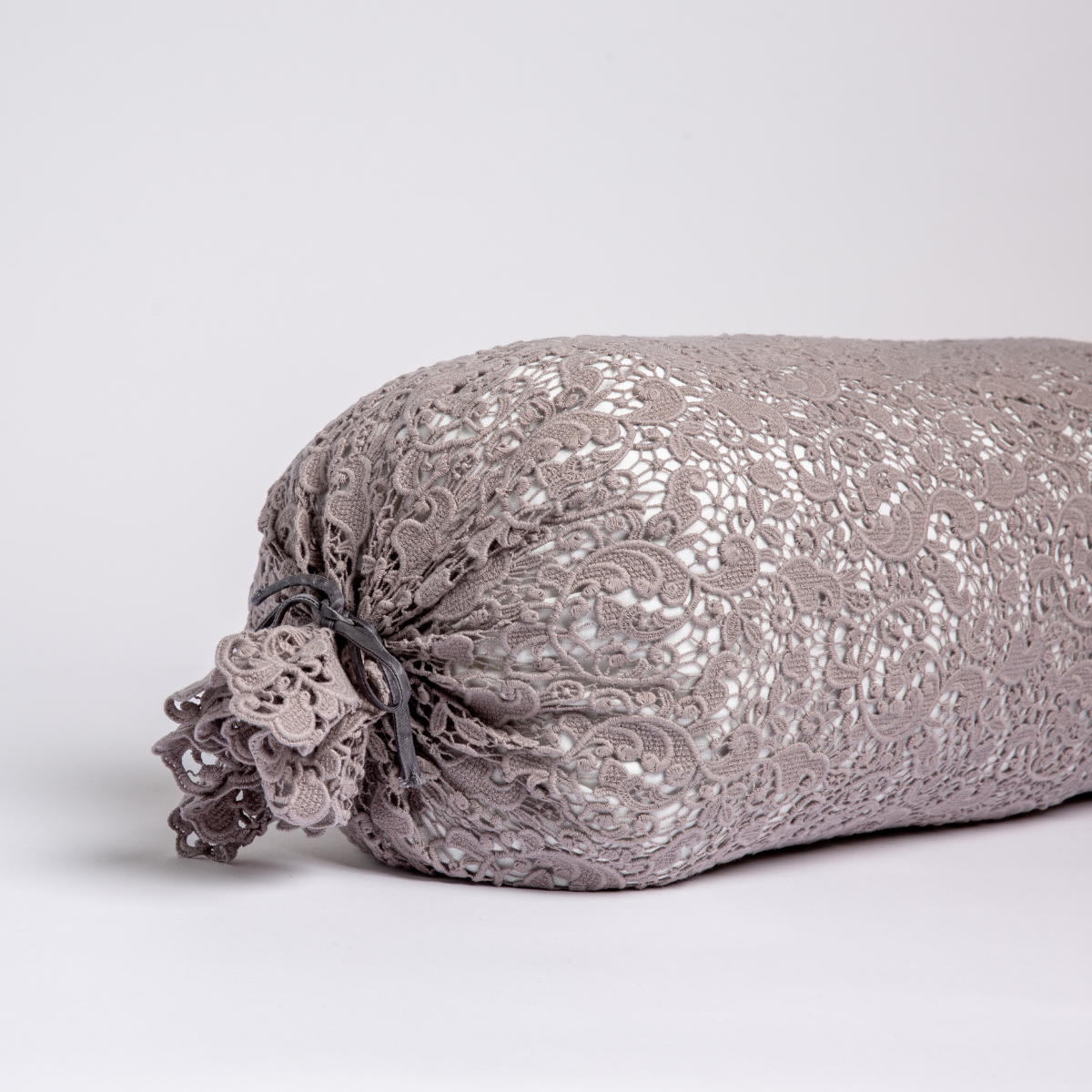 Moonlight:  one end of a lace boslter cover on a winter white liner against a white background. 