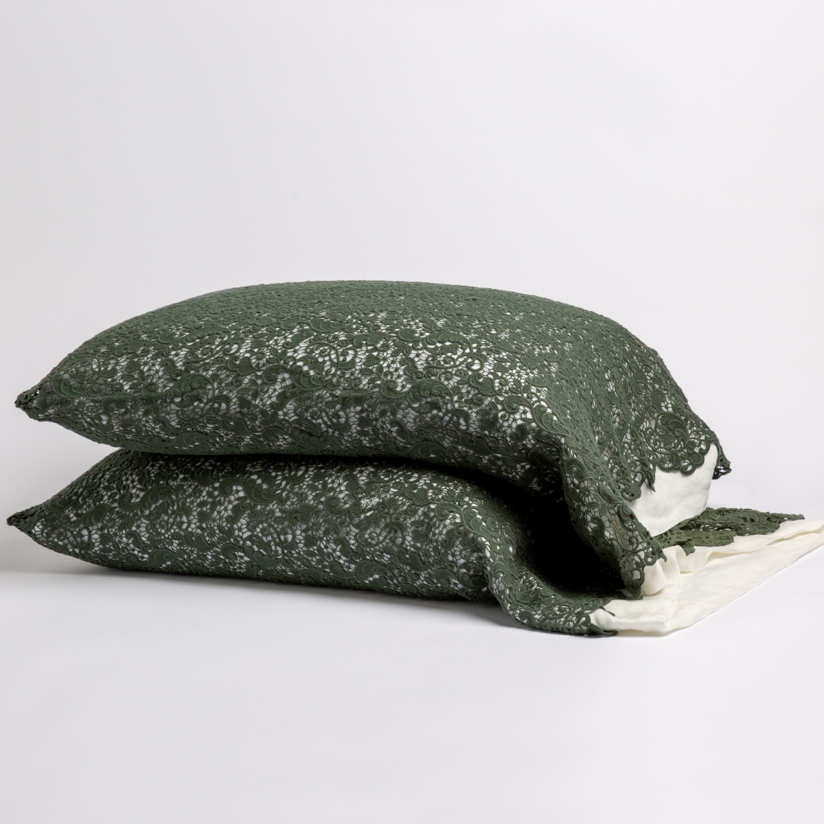 Juniper: a pair of stacked cotton lace pillowcase covers on winter white liners against a white background. 