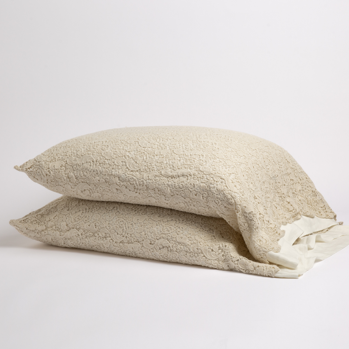 Parchment: a pair of cotton lace pillowcase covers on winter white liners against a white background. 