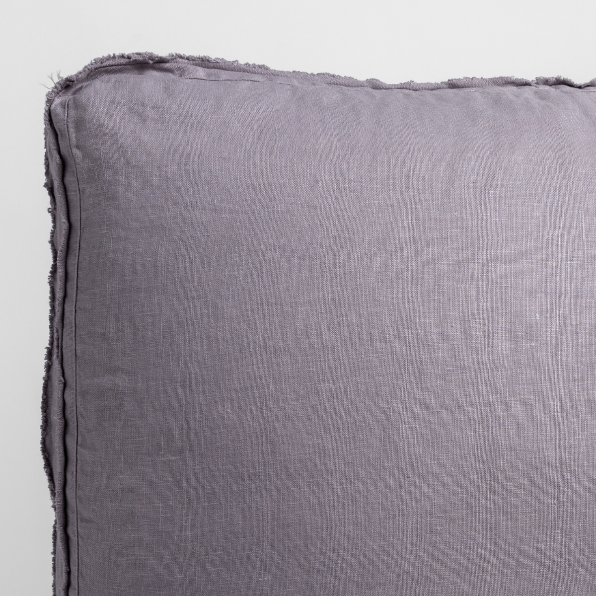 French Lavender: close up of midweight linen pillow corner with raw edges trimming its gusset. 