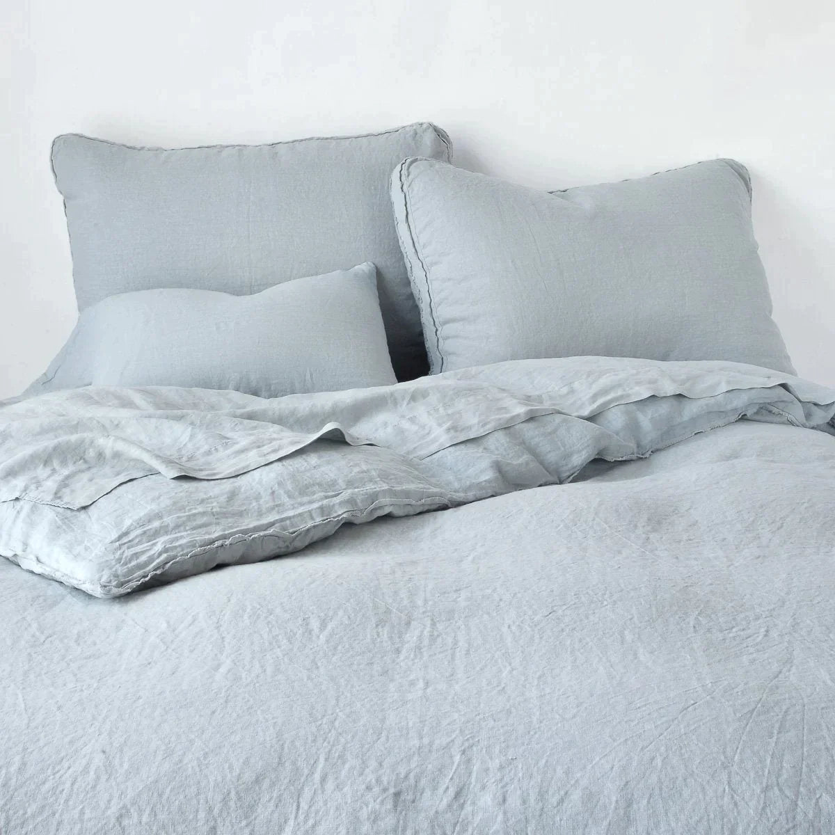 Mineral: Midweight linen shams shown from foot of bed, leaning against a plain background with monochromatic bedding. 