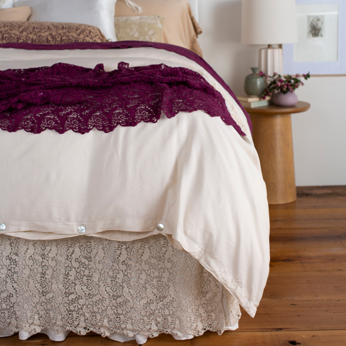 [allvariants]: cotton lace bed skirt and bed scarf shown from the foot of the bed dressed in light tones with pops of color. 