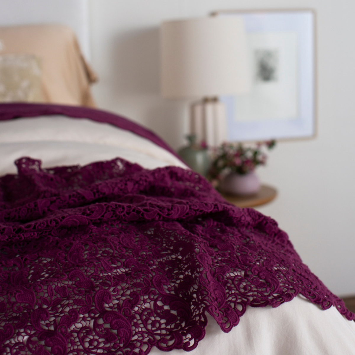 : a close up of the lace bed scarf rumpled at the foot of a bed, the rest of the shot is out of focus. 