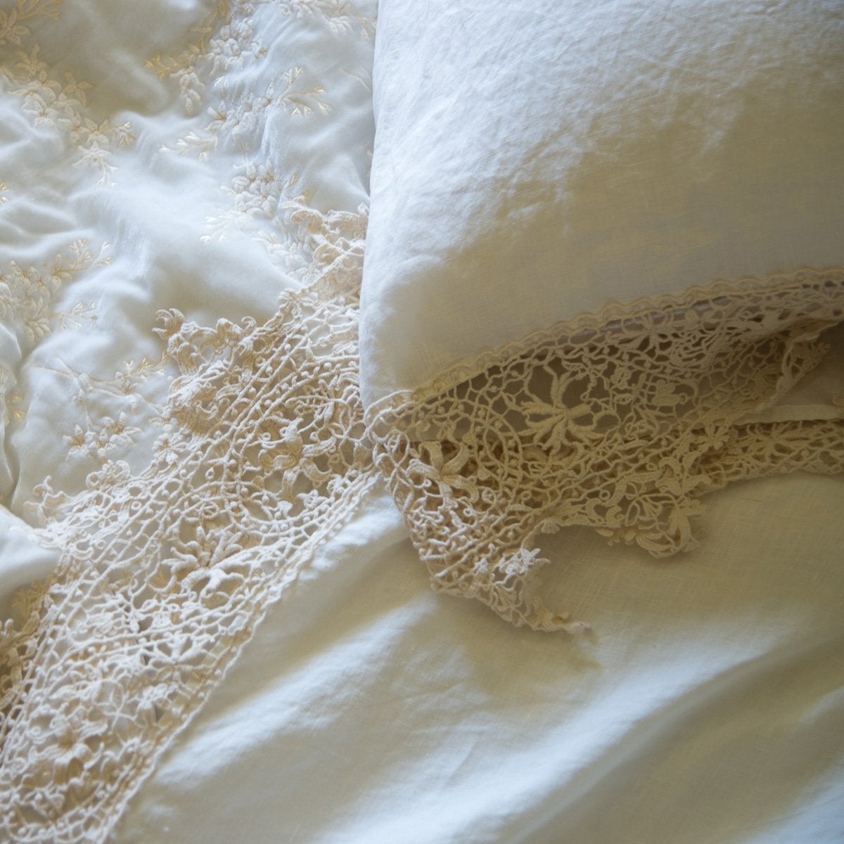 : Close up of Frida lace detail in winter white pillow case and matching sheet, highlighting the antique cotton lace pattern - overhead view.