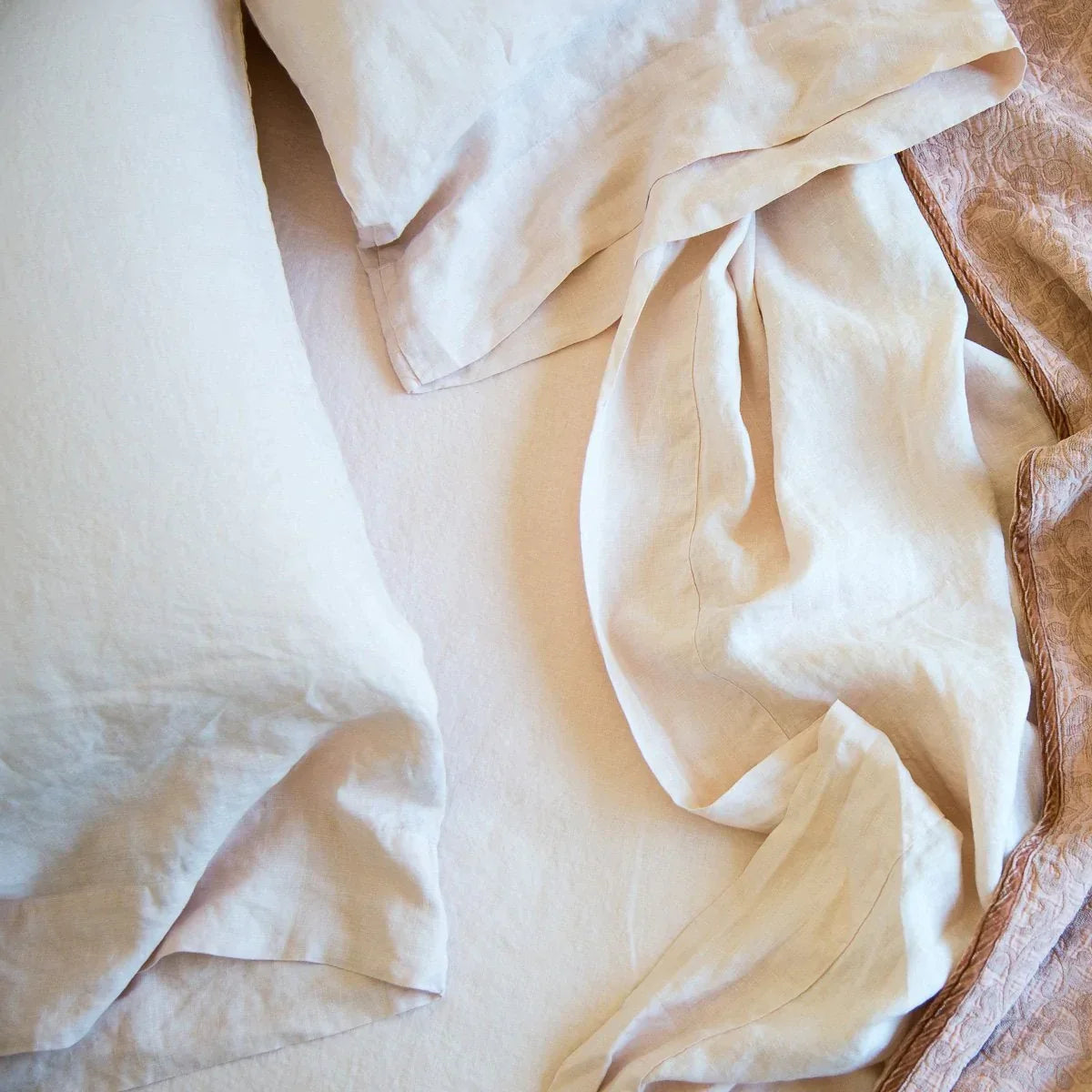 : Rumpled linen sheeting and pillow cases with Vienna cotton chenille jacquard in soft pink tones - overhead view.