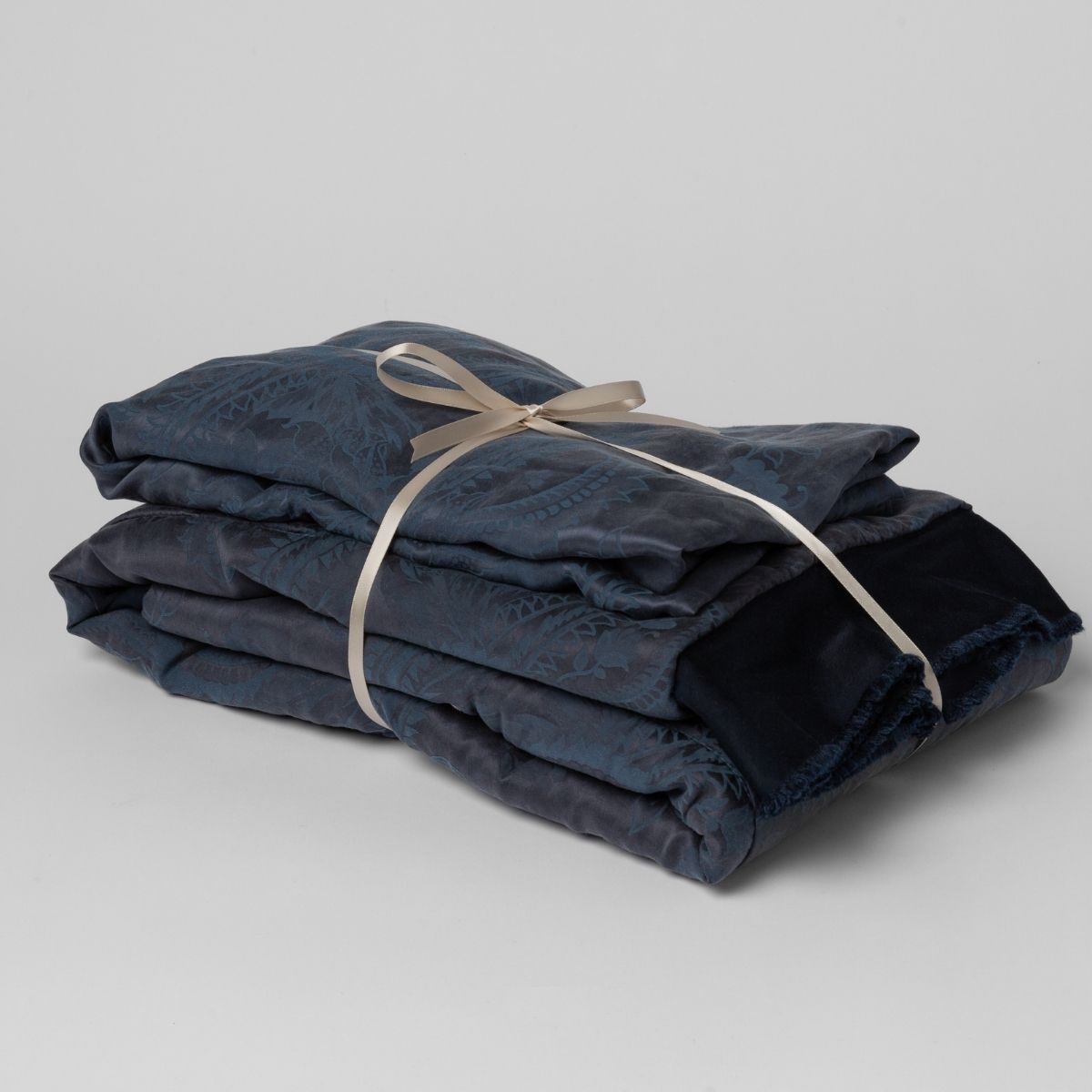 Midnight:  matching crib sheet and baby blanket bundled and tied with a ribbon against a white background.