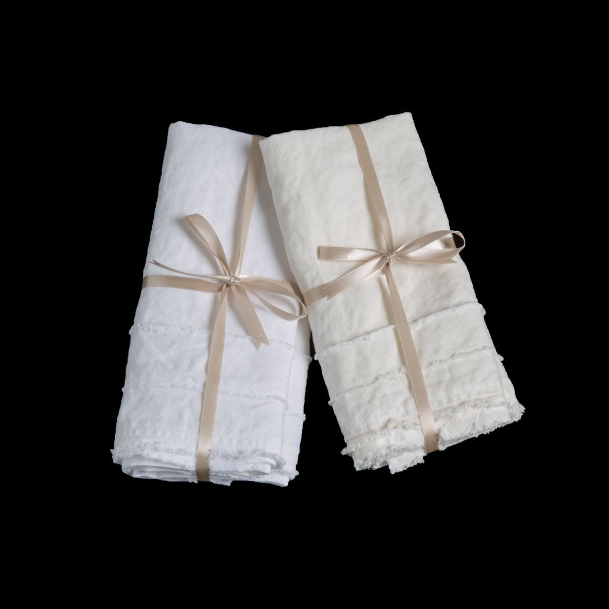 : white and winter white midweight linen guest towels tied with ribbons against a black background.