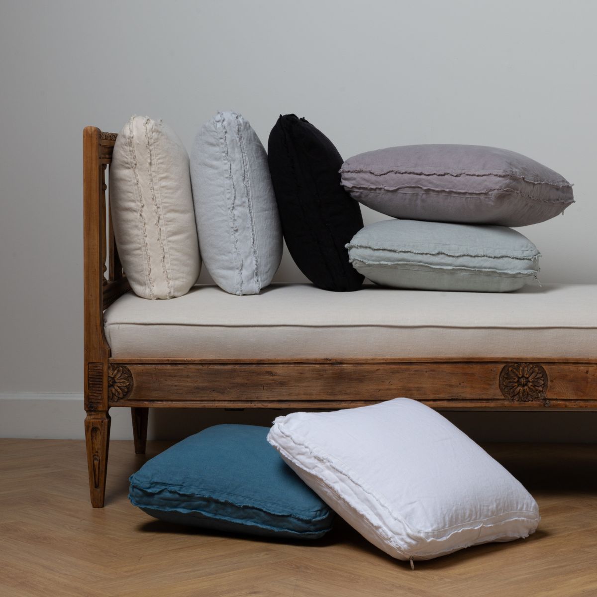 : daybed bench with multiple midweight linen throw pillows both on the daybed and on the floor. 
