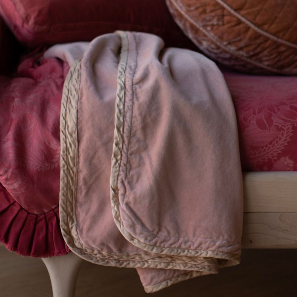 [allvariants]: cotton velvet baby blanket trimmed in charmeuse shown close up on a toddler bed with vibrant red tones. 