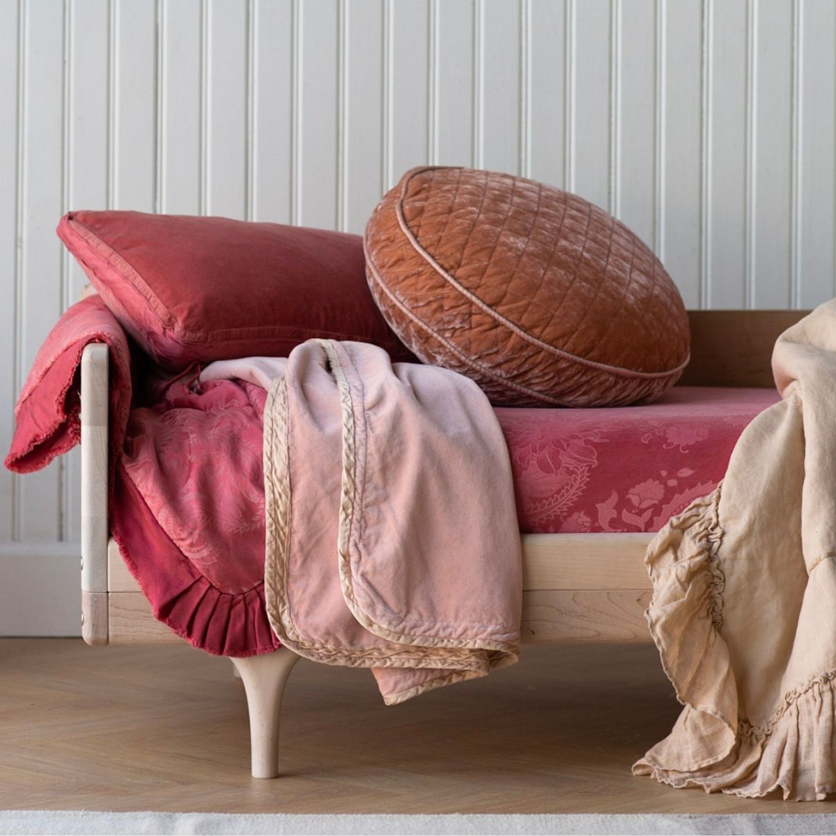 [allvariants]: a closeup of the end of a toddler bed dressed in feminime colors. 