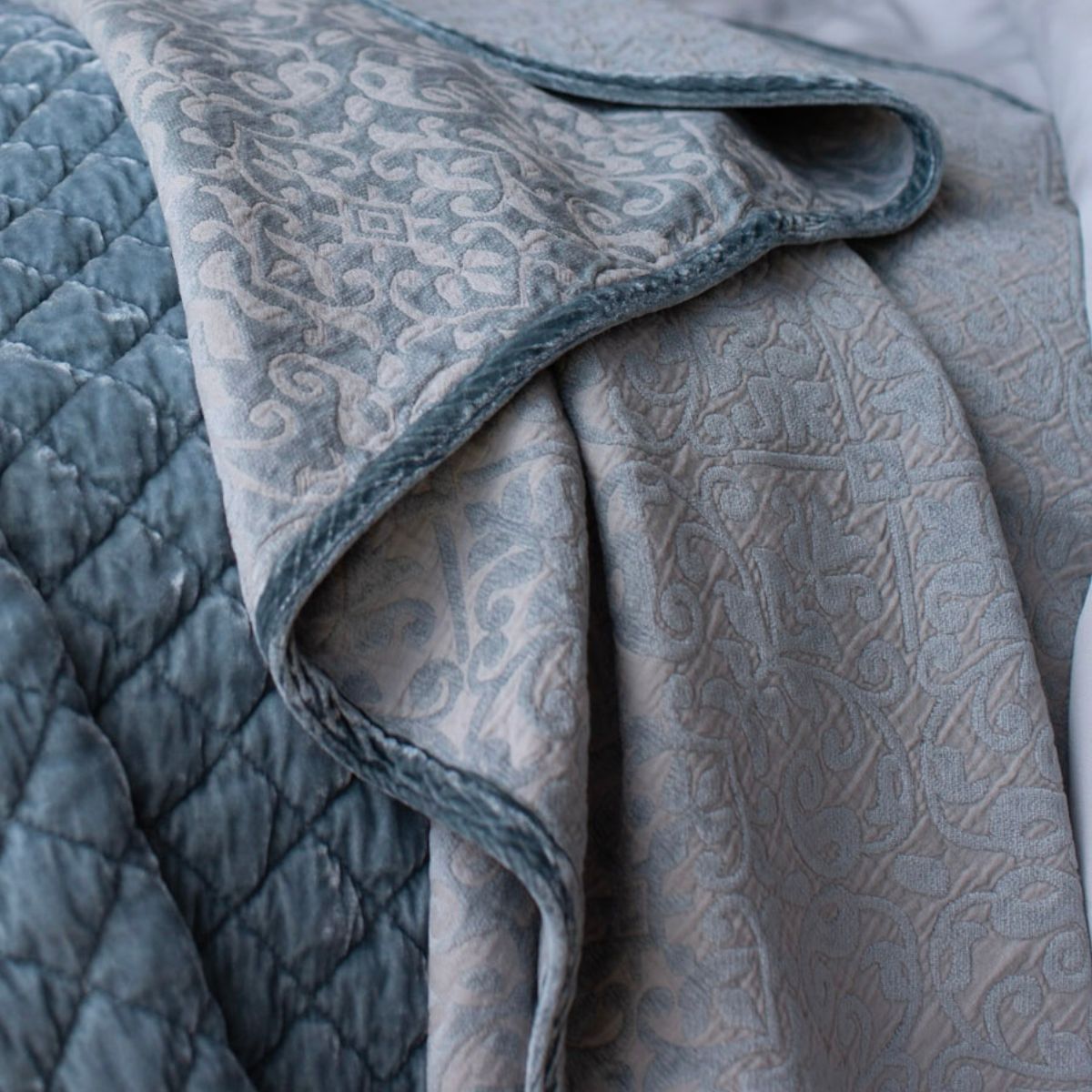 [allvariants]: cotton chenille baby blanket shown draped  off of bed highlighting the trim detail and chenille pattern. 