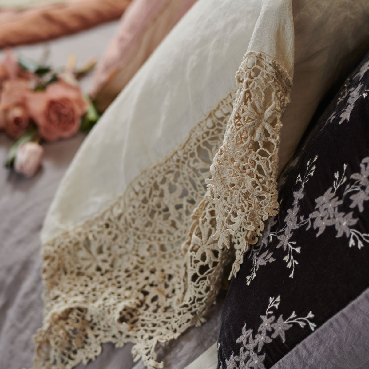 : Close up of parchment Frida pillowcase over moonlight bedding, highlighting antique cotton lace detail - side view.