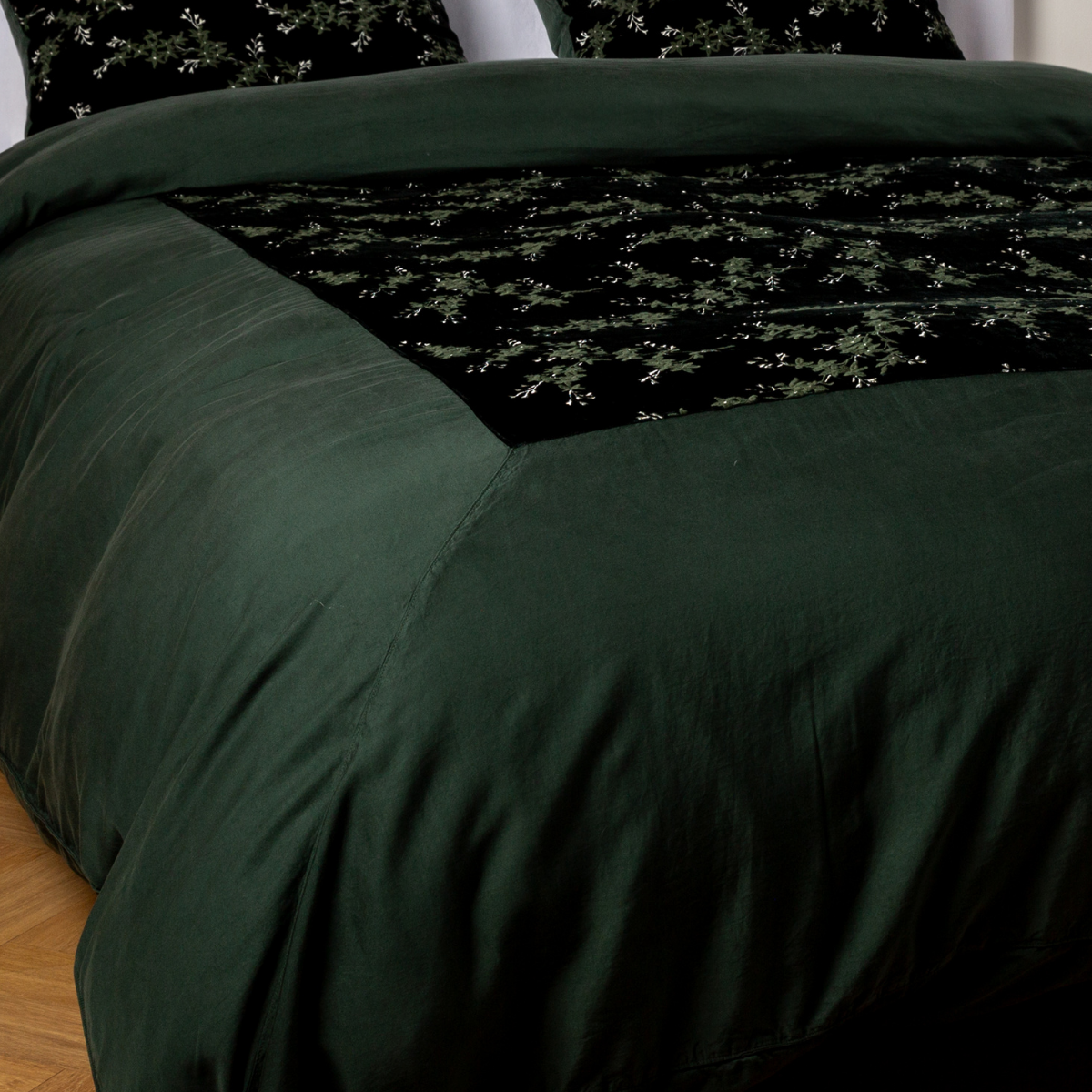 Juniper: A close-up of the mitered corner of an embroidered silk velvet and tencel duvet cover — its matching shams barely visible in the shot. 