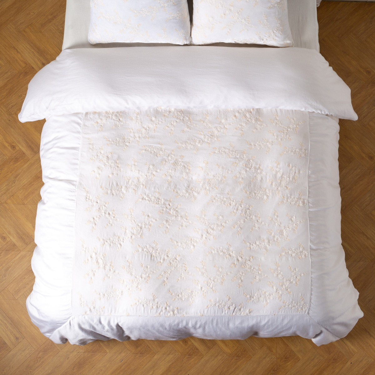 White: An overhead shot of an embroidered silk velvet and tencel duvet cover and matching shams. 
