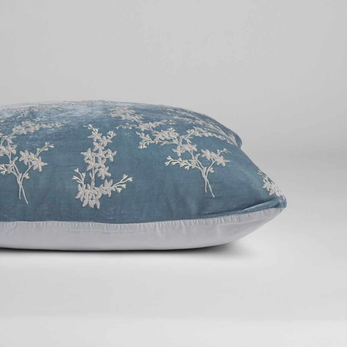 Cloud: A close-up of the sham shown on its side to display the embroidered silk velvet face and tencel back — shown against a white background. 
