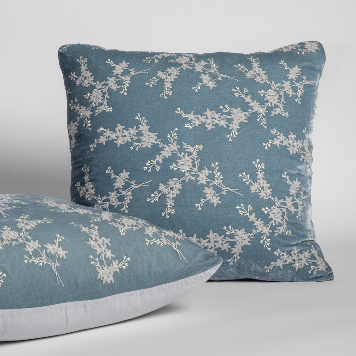 Cloud: A pair of shams shown against a white background with one sham upright and the other on its side to show the tencel back and embroidered silk velvet face. 