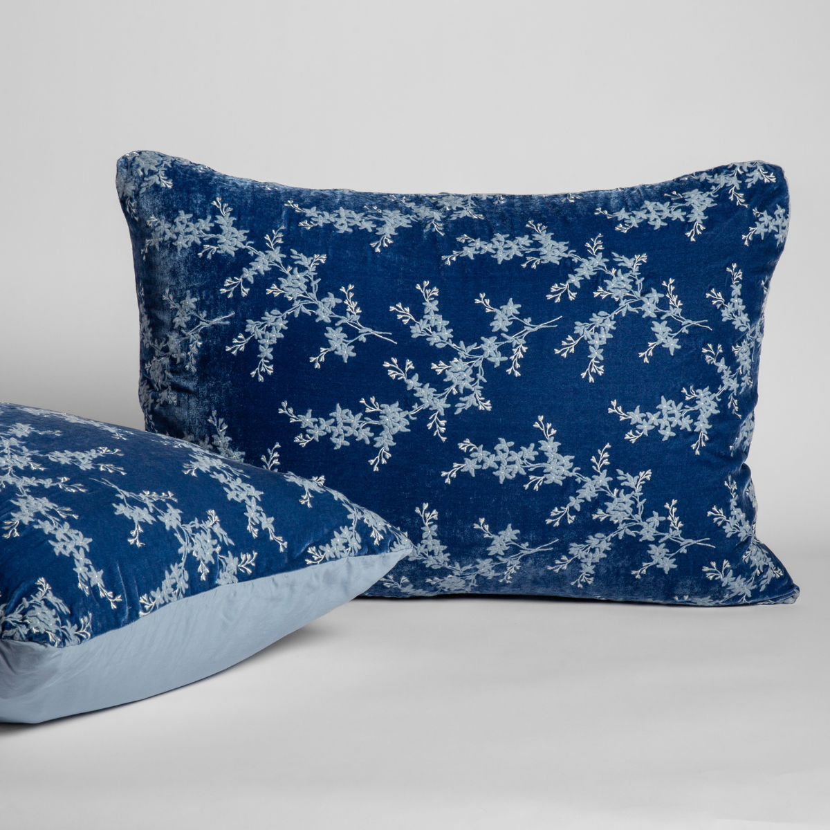 A pair of shams shown against a white background with one sham upright and the other on its side to show the tencel back and embroidered silk velvet face. 