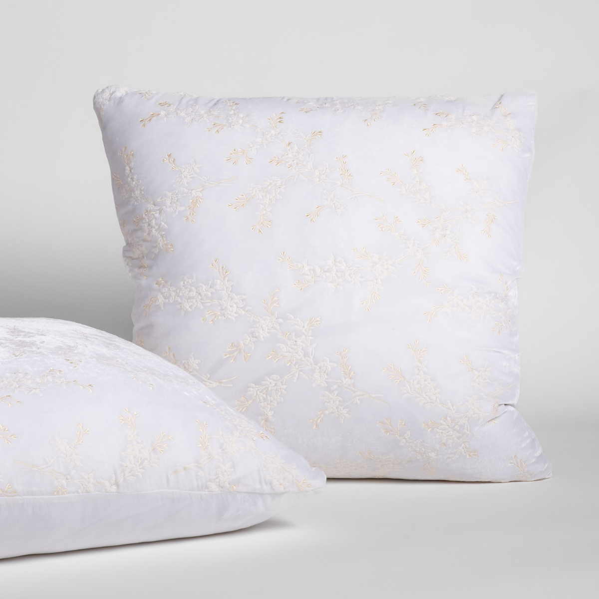 White: A pair of shams shown against a white background with one sham upright and the other on its side to show the tencel back and embroidered silk velvet face. 