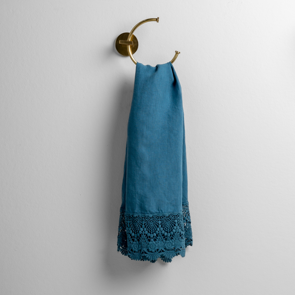 Cenote: linen with mattine lace trimmed guest towel on a decorative towel ring mounted on a white wall. 