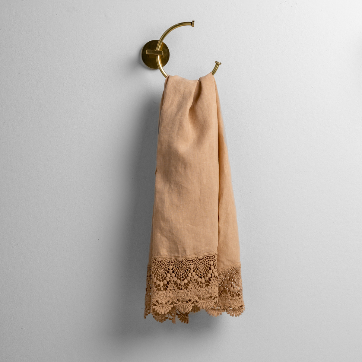 Honeycomb: linen with mattine lace trimmed guest towel on a decorative towel ring mounted on a white wall. 