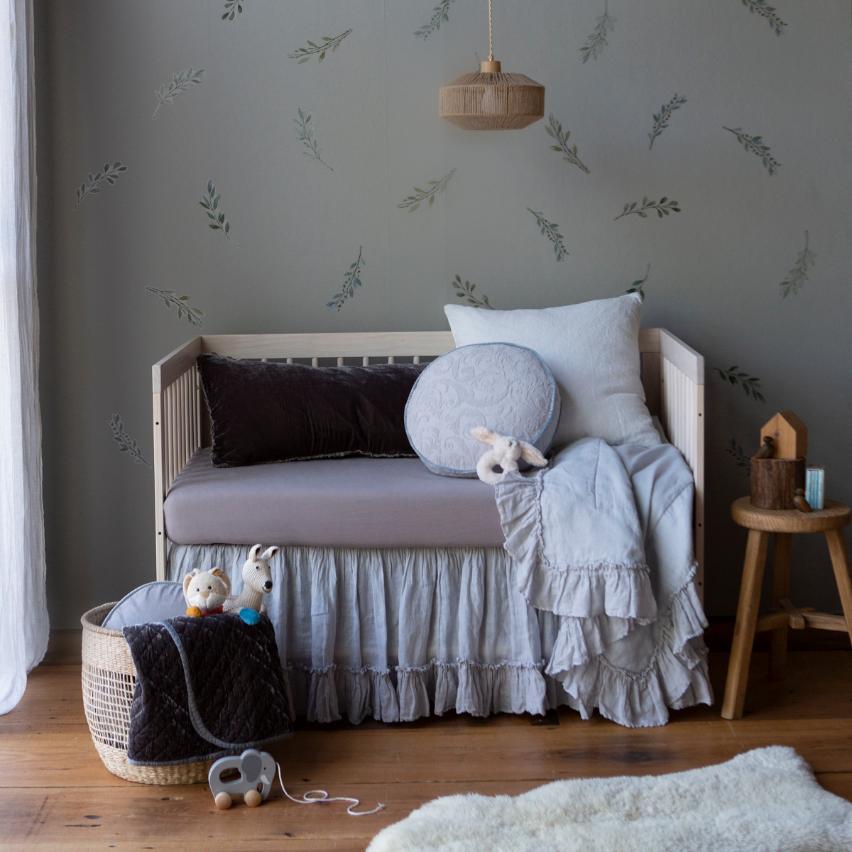 [allvariants]: Crib sheet in moonlight on a grey and light blue toned bed in a nursery with warm wood accents.