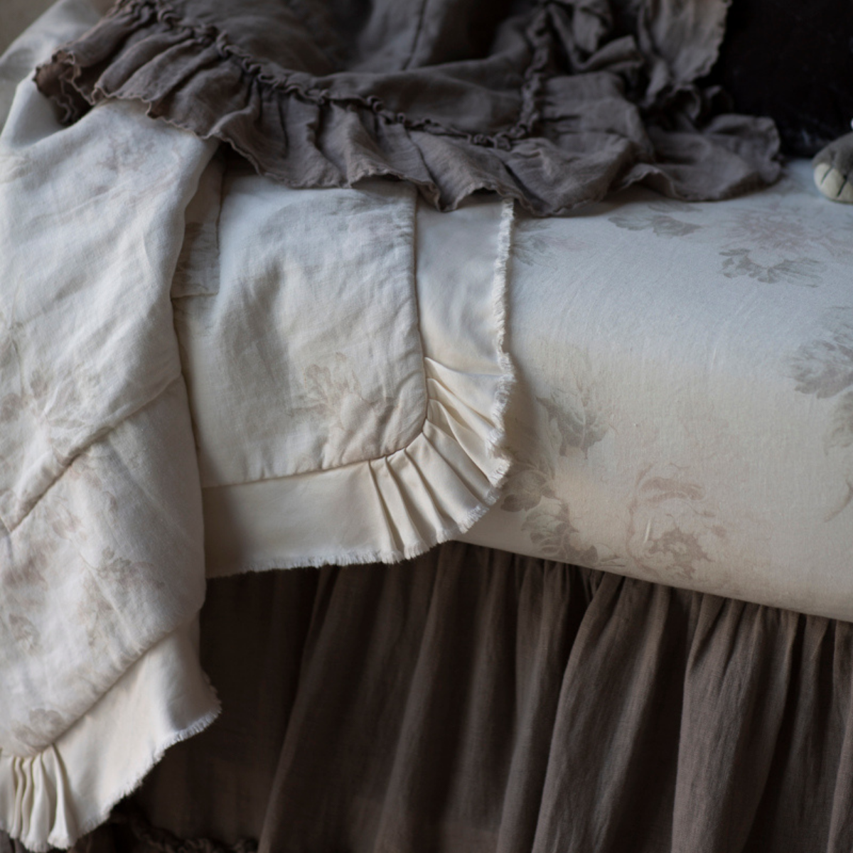 [allvariants]: Close up of blanket and crib sheet showcases the muted floral pattern of the linen and the satin trim detail.