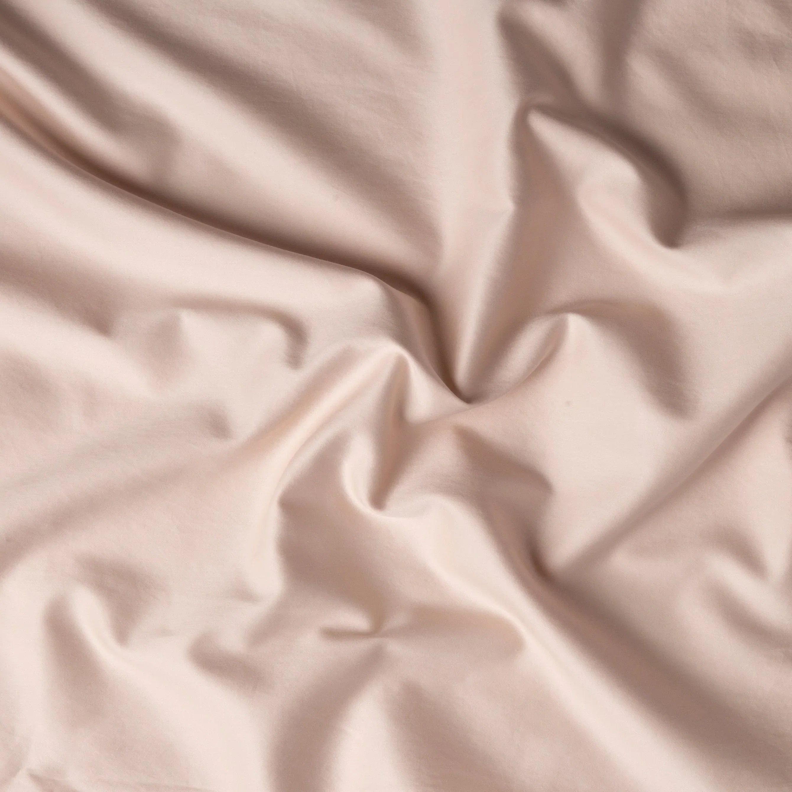 Pearl: A close up of cotton sateen fabric in pearl, a nude-like, soft rose pink tone. 
