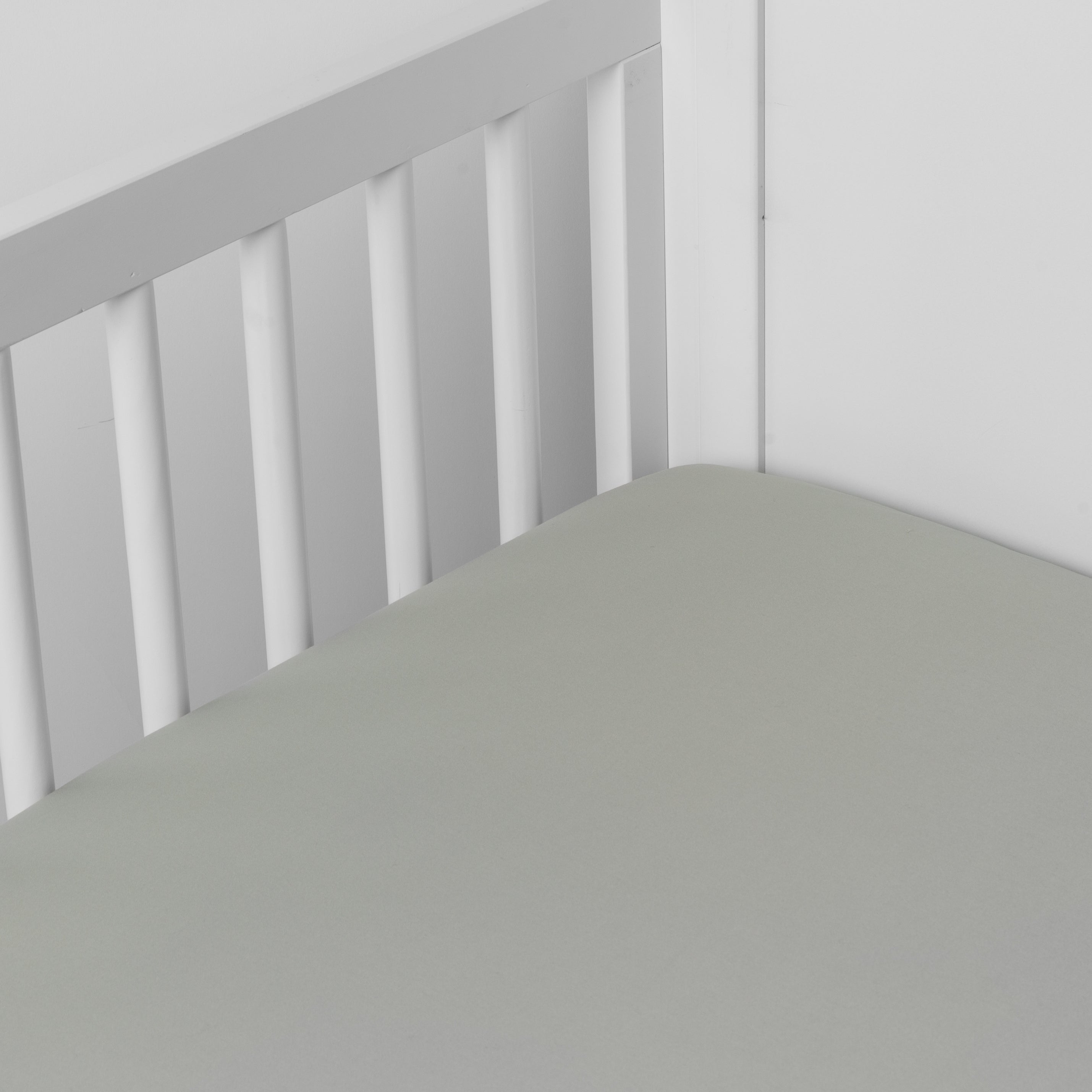 Eucalyptus: Cotton sateen crib sheet shown from a slight overhead angle into  an inside corner of a crib. 