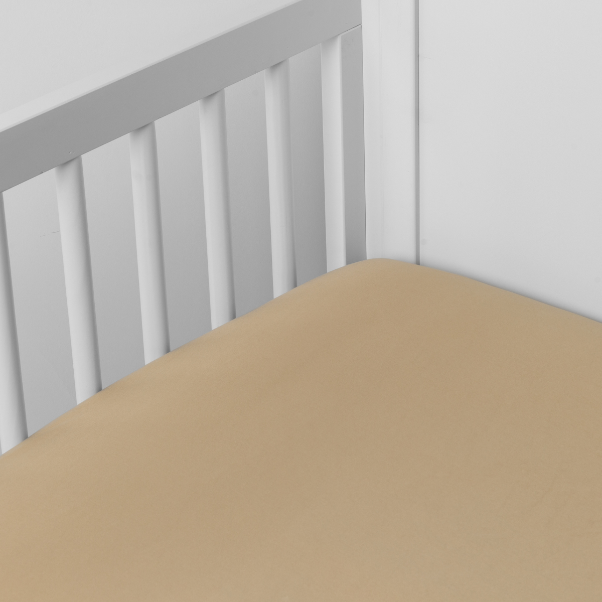 Honeycomb: Cotton sateen crib sheet shown from a slight overhead angle into  an inside corner of a crib. 