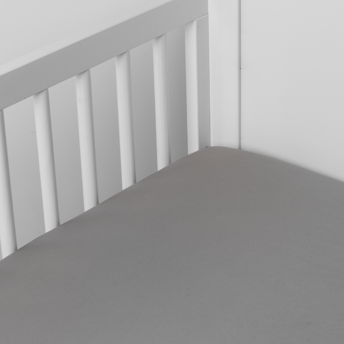Mineral: Cotton sateen crib sheet shown from a slight overhead angle into  an inside corner of a crib. 