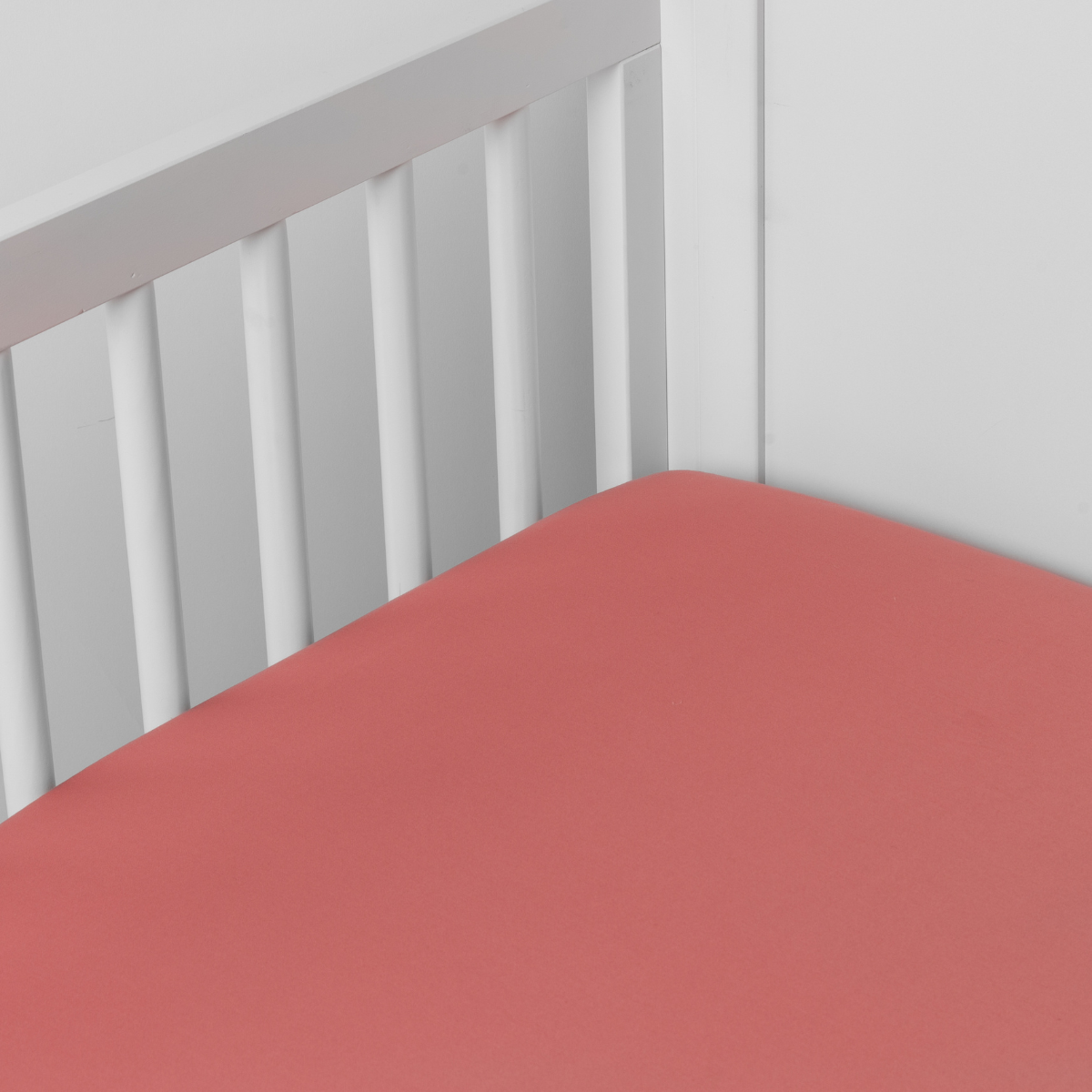 Poppy: Cotton sateen crib sheet shown from a slight overhead angle into  an inside corner of a crib. 