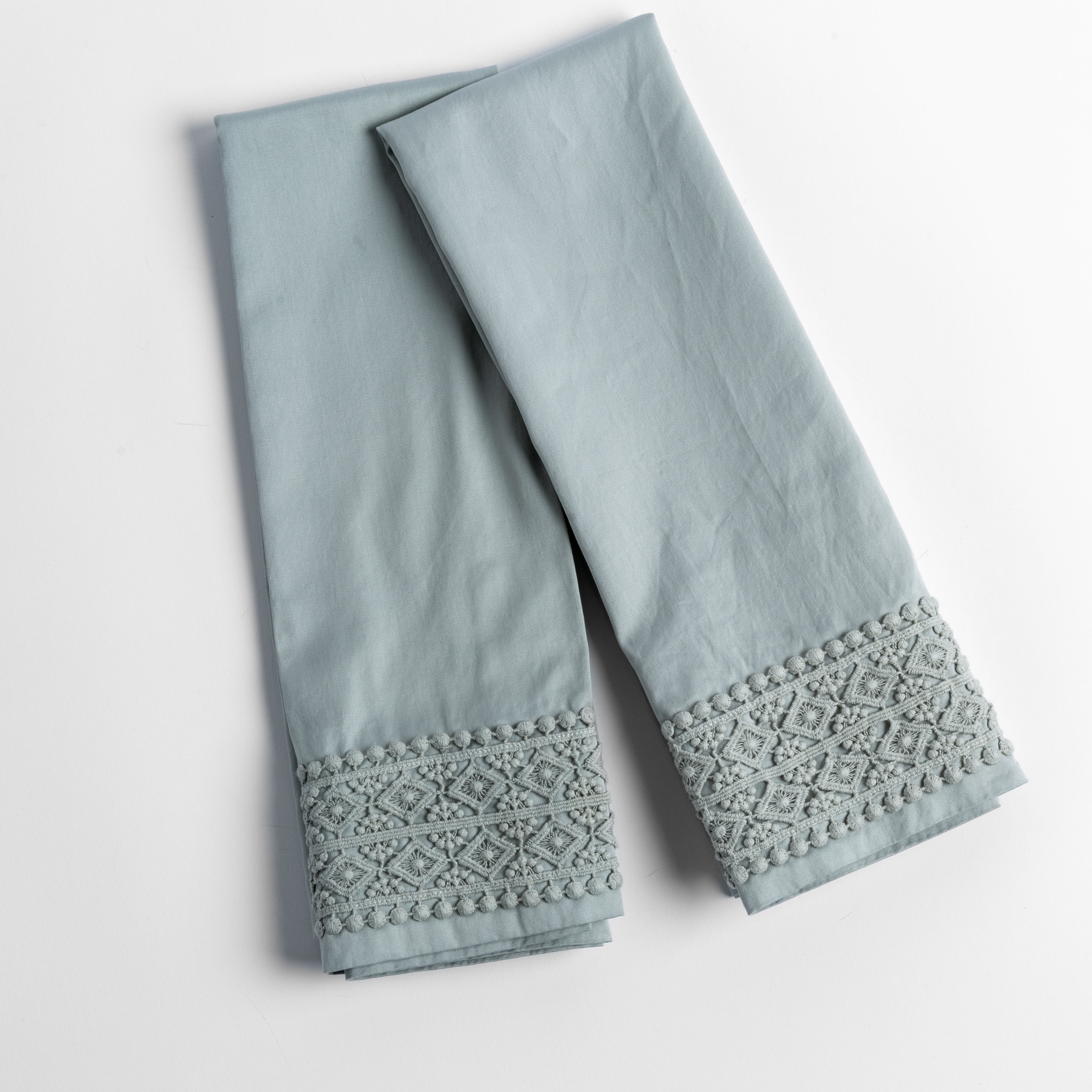 An overhead shot of a folded pair of lace trimmed pillowcases shown side by side and slightly overlapping.