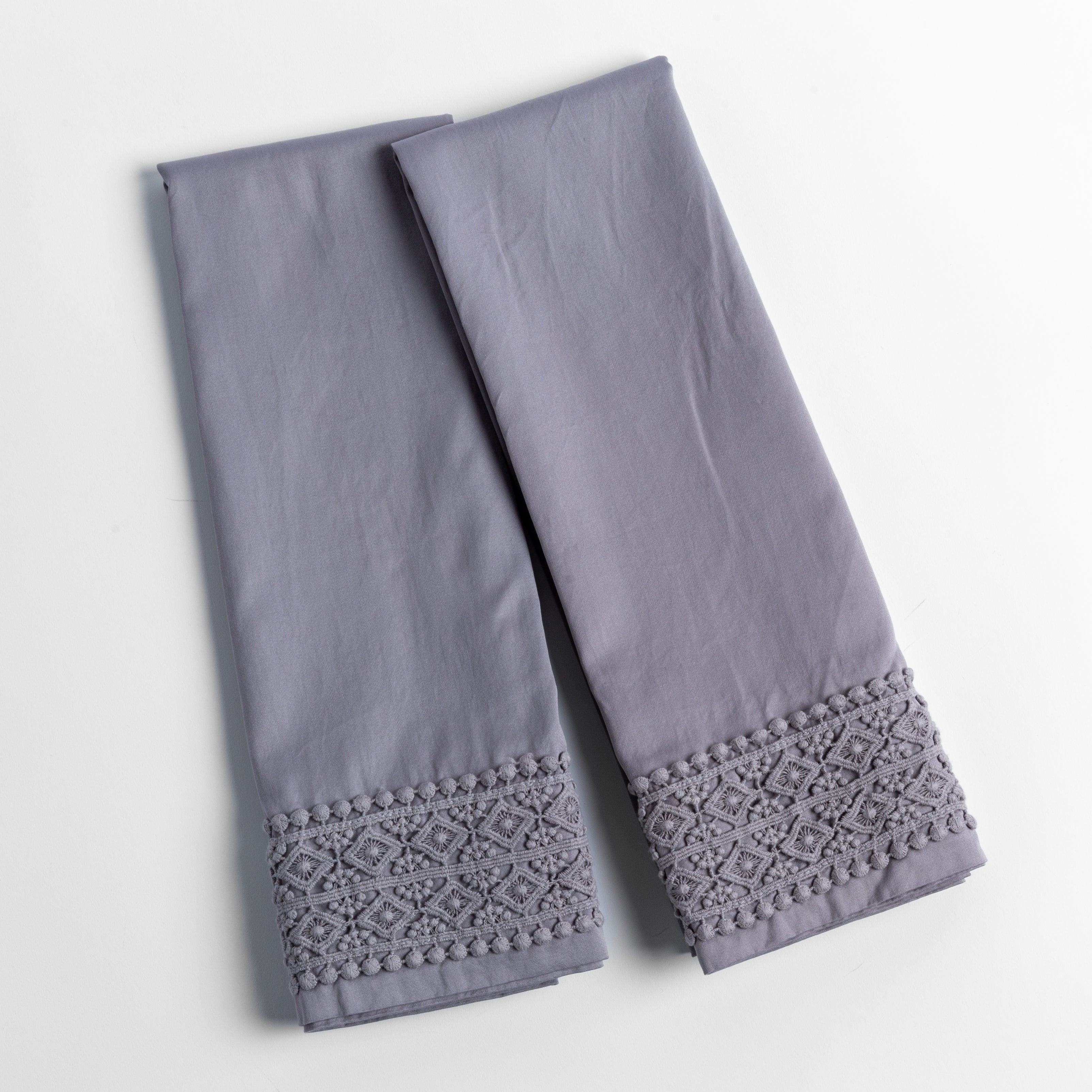 An overhead shot of a folded pair of lace trimmed pillowcases shown side by side and slightly overlapping.