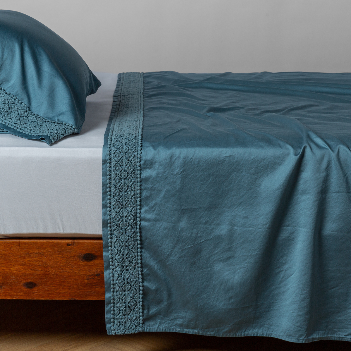 Matching lace trimmed cotton sateen flat sheet and pillowcase shown with a winter white fitted sheet - side view. 