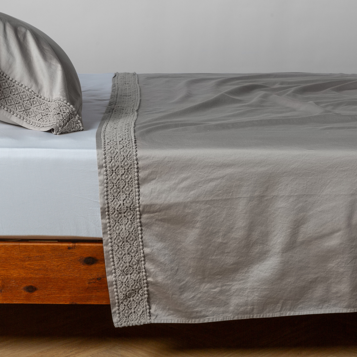 Matching lace trimmed cotton sateen flat sheet and pillowcase shown with a winter white fitted sheet - side view. 