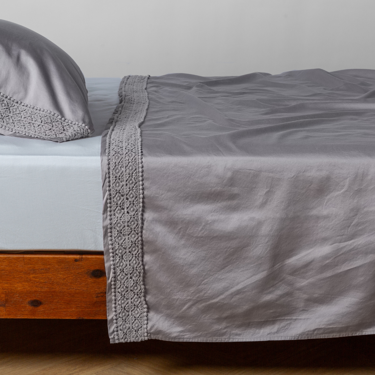 Matching lace trimmed cotton sateen flat sheet and pillowcase shown with a winter white fitted sheet - side view. 