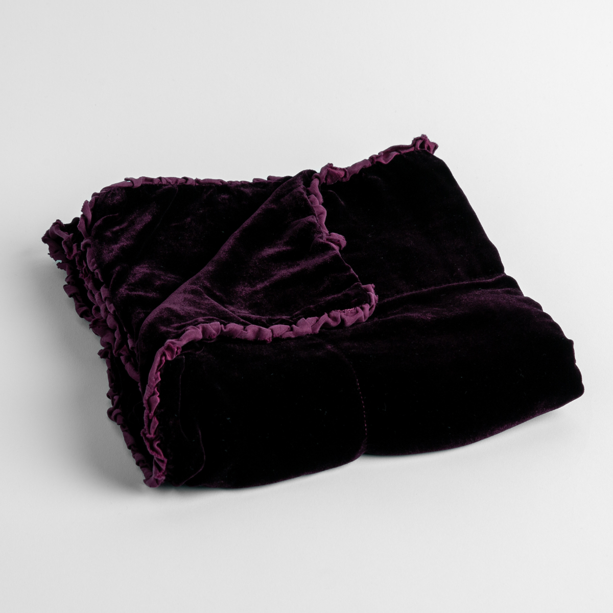 Fig:  silk velvet baby blanket with charmeuse trim shown slightly overhead with a corner folded back to show trim detail against a white background. 