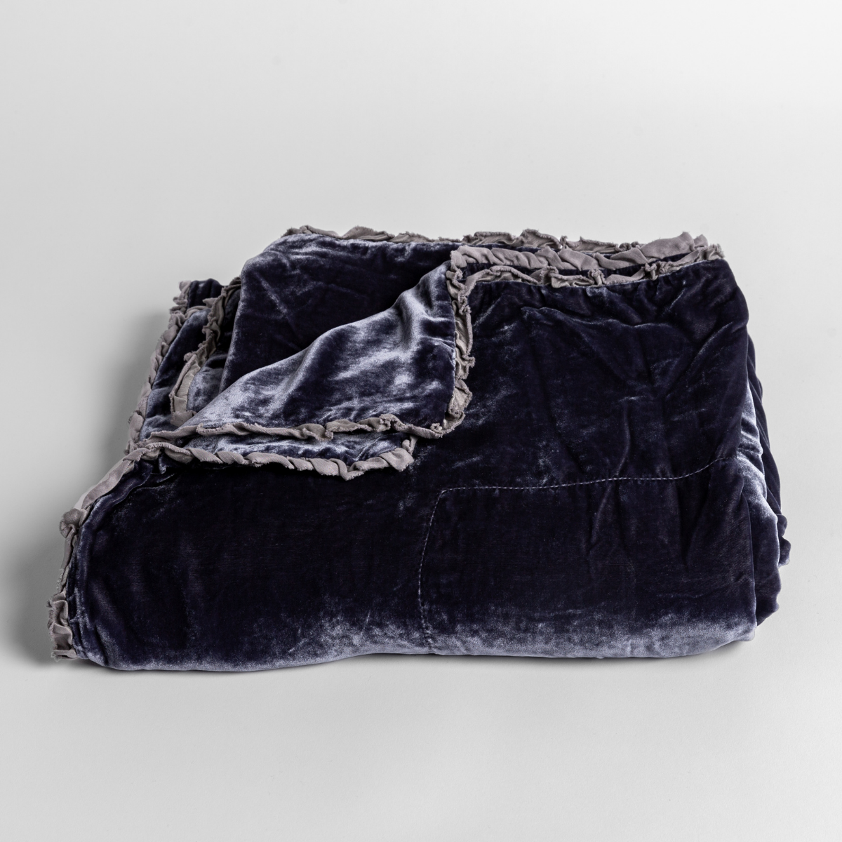 French Lavender: silk velvet baby blanket with charmeuse trim shown slightly overhead with a corner folded back to show trim detail against a white background. 