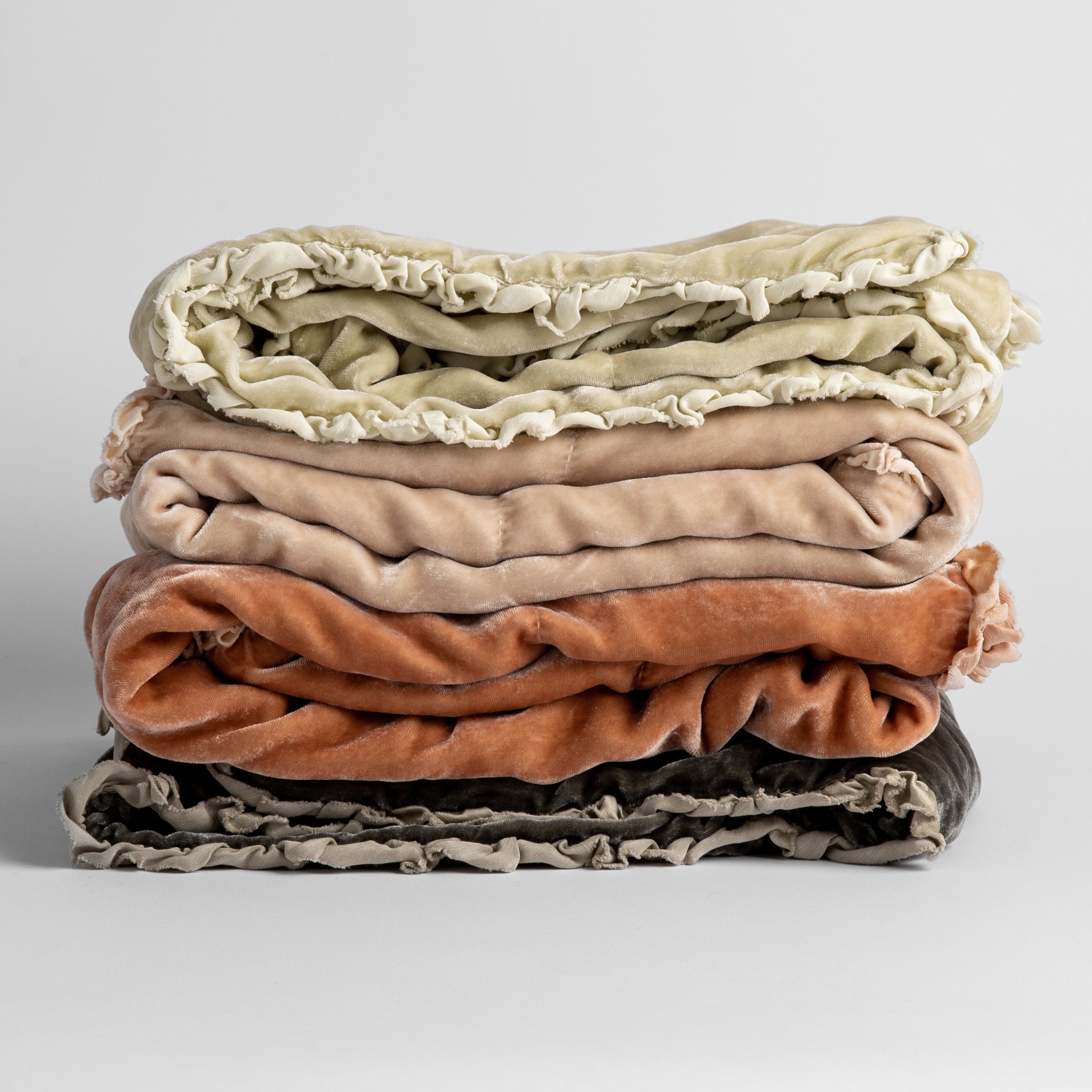[allvariants]: stack of four silk velvet baby blankets with charmeuse trim shown against a white background.  Blankets shown in Parchment, Pearl, Rouge and Fog. 
