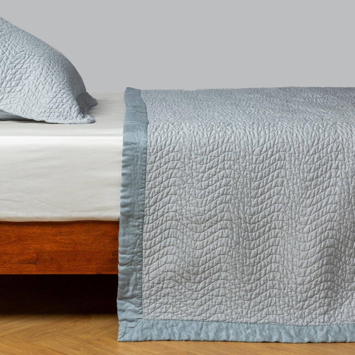 Cloud: quilted cotton sateen coverlet with matching sham on a winter white fitted sheet - side view. 