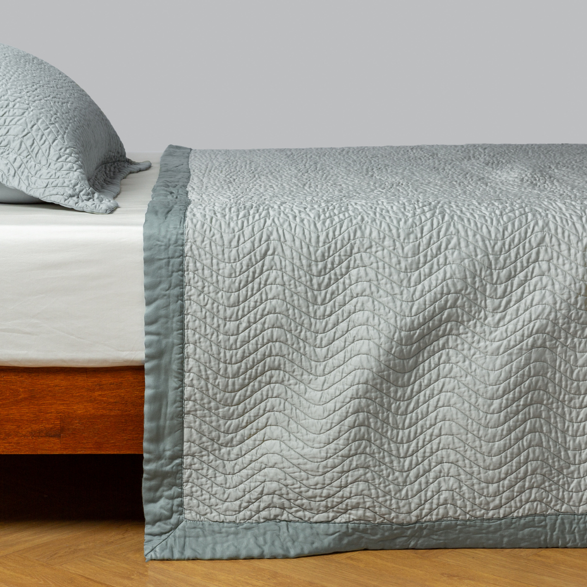 Eucalyptus: quilted cotton sateen coverlet with matching sham on a winter white fitted sheet - side view. 
