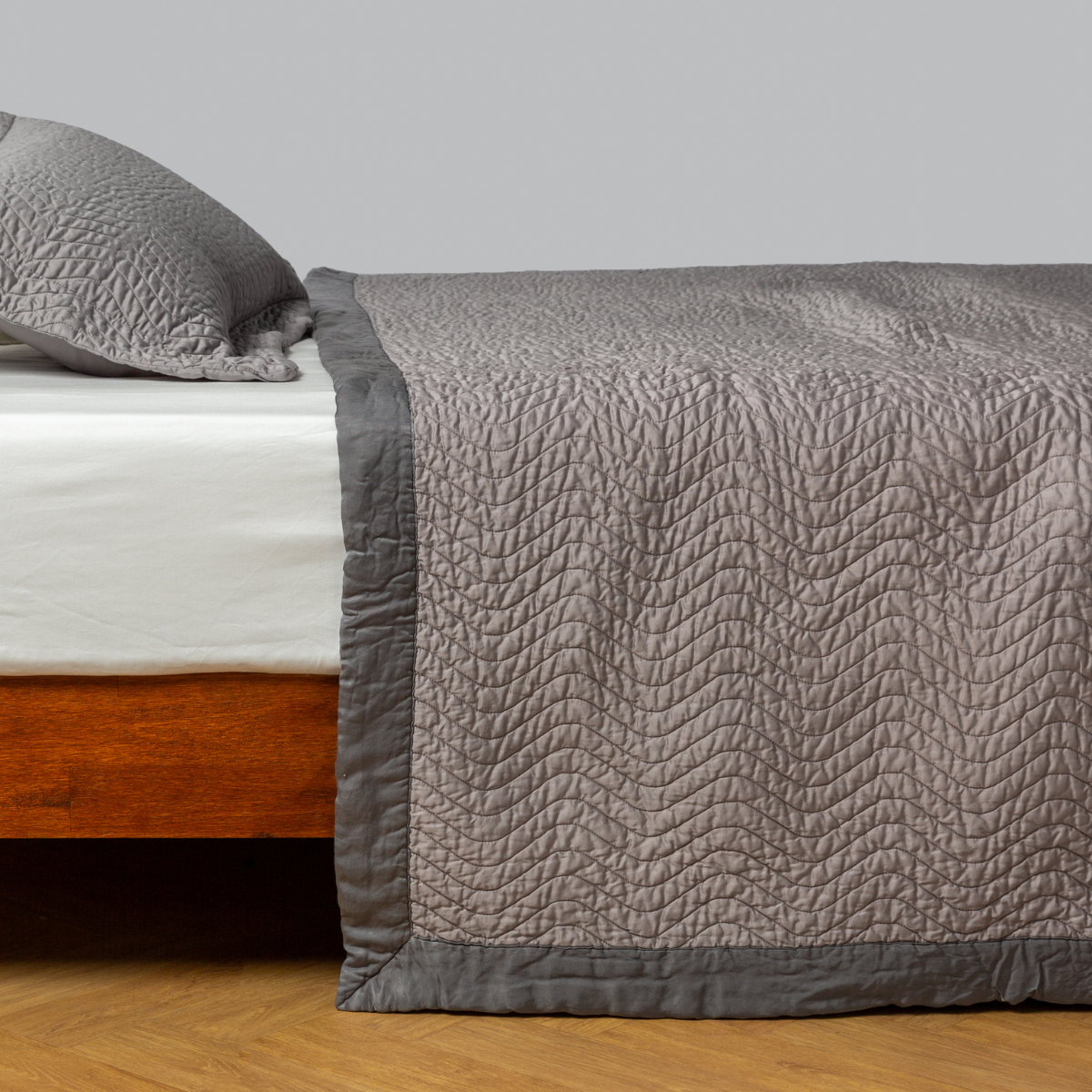 Fog: quilted cotton sateen coverlet with matching sham on a winter white fitted sheet - side view. 