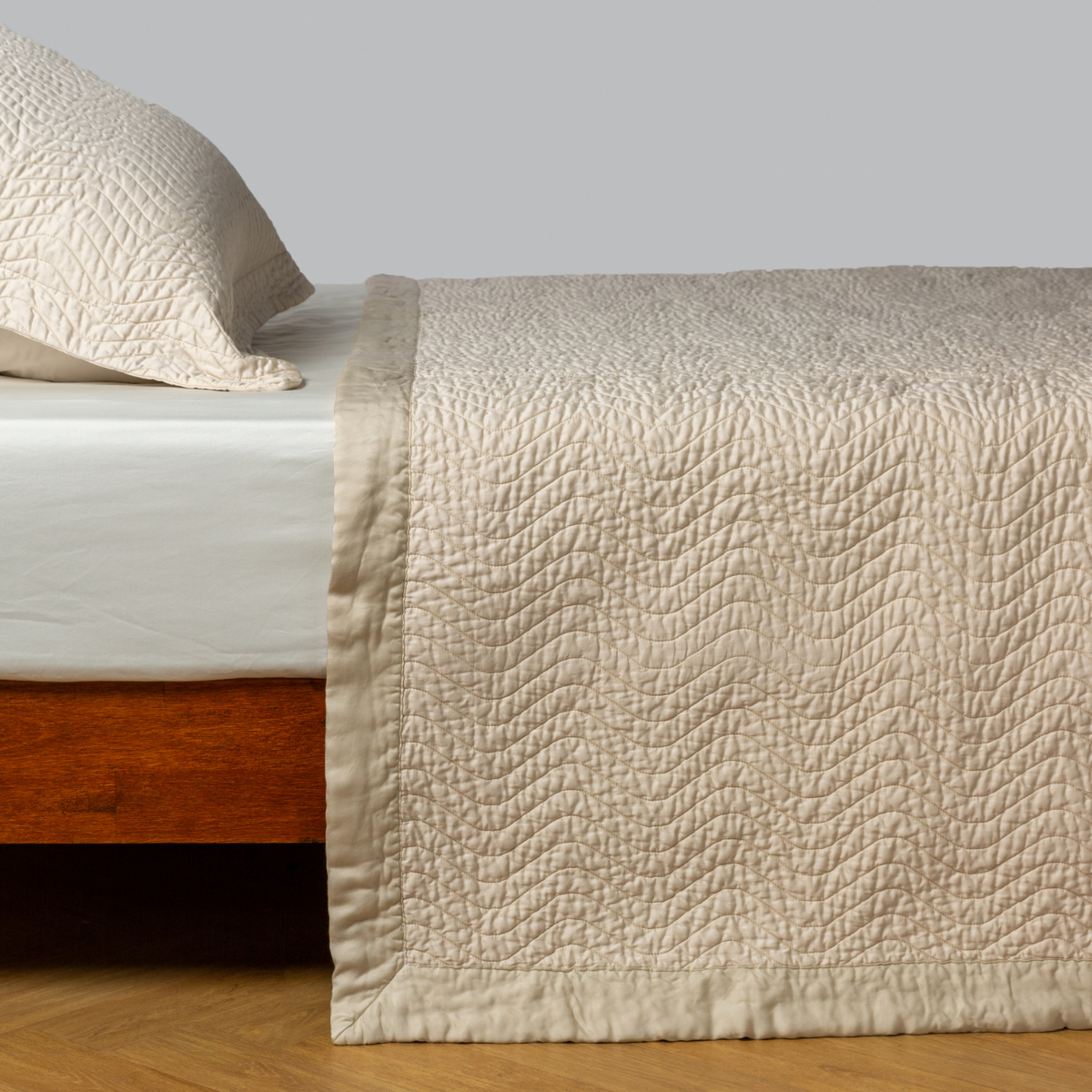 Parchment: quilted cotton sateen coverlet with matching sham on a winter white fitted sheet - side view. 