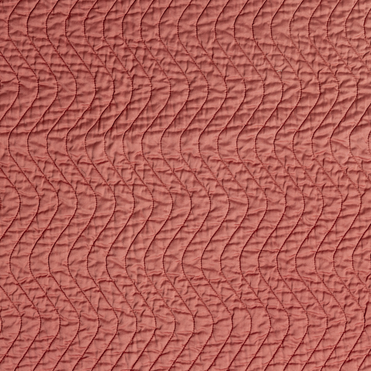 Poppy: A close up of quilted cotton sateen fabric in poppy, a warm coral pink.