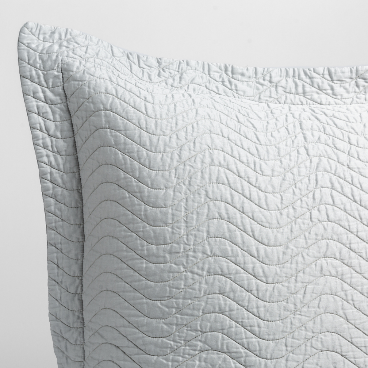 Cloud: a close up of a pillow corner showing the flange framing quilted cotton sateen shot against a white background. 