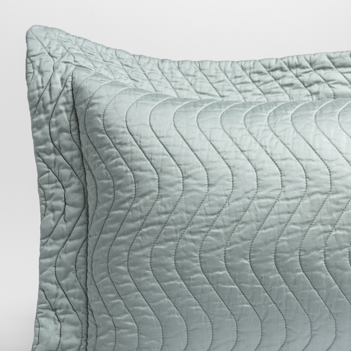 Eucalyptus: close up of the corner of a quilted cotton sateen pillow sham - shot against a white background. 