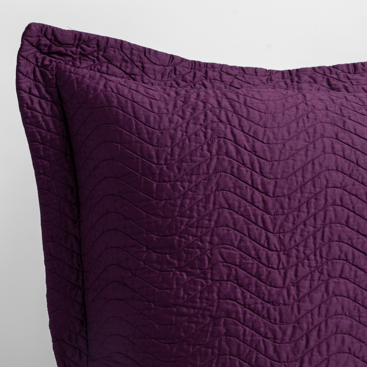 Fig: a close up of a pillow corner showing the flange framing quilted cotton sateen shot against a white background. 