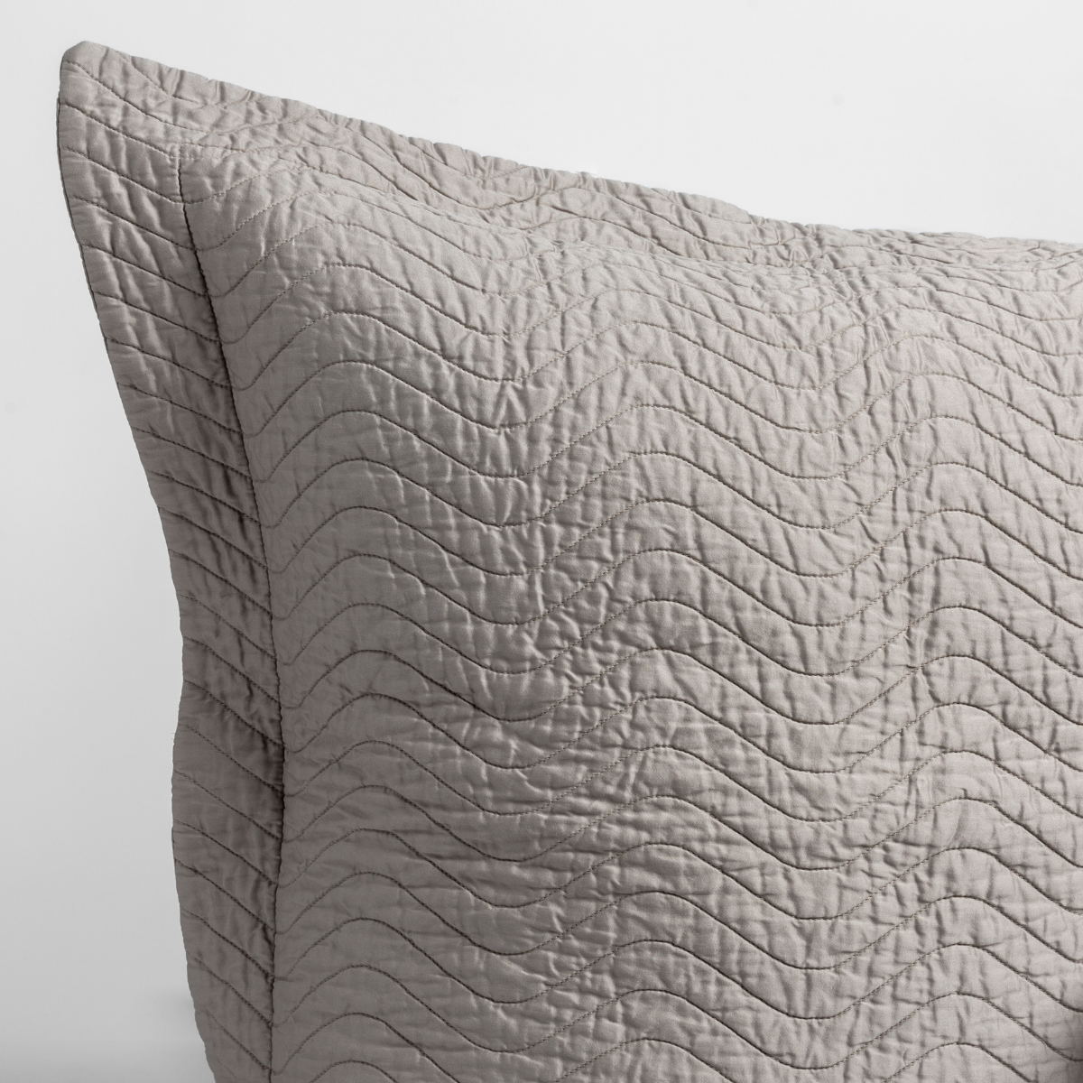Fog: a close up of a pillow corner showing the flange framing quilted cotton sateen shot against a white background. 